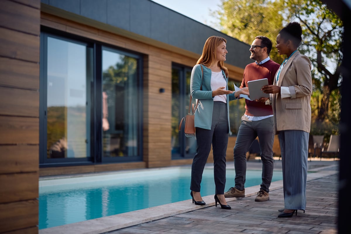 A real estate professional talking with a homeowner in front of their house